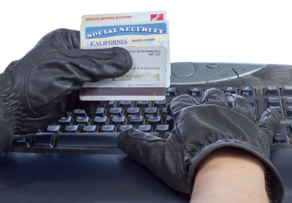 Identification documents (social security, driver license and credit cards) in hand of thief, isolated on white. Identity theft