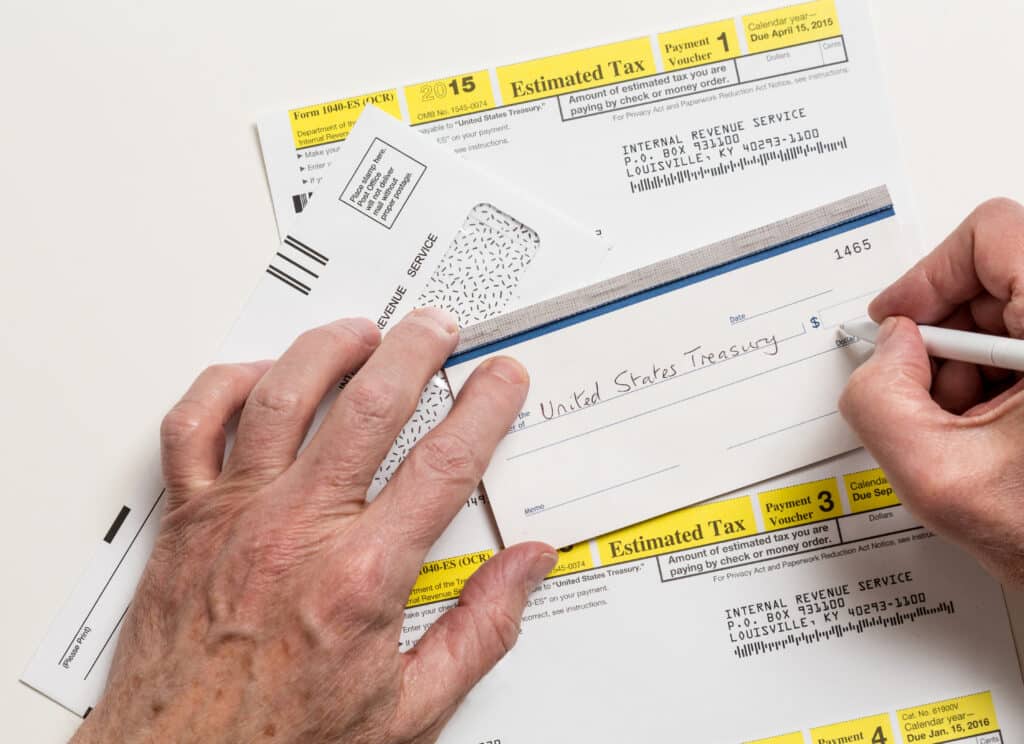 Male  hands writing check to Internal revenue service IRS form 1040-ES for payment of estimated taxes in 2024