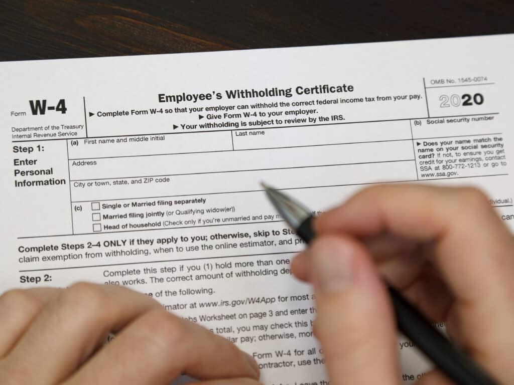 An IRS W-4 Employee’s Withholding Certificate form, newly revised and issued in 2020, is shown up close just before being filled out by hand.