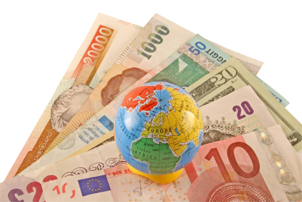 A globe sitting on a selection of international currencies, illustrating the global benefits of FEIE for expatriates.
